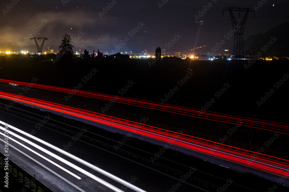 Two side Traffic on the A22 Autobahn in South Tirol, Bolzano in the Background. Long exposure of Light trails at night.