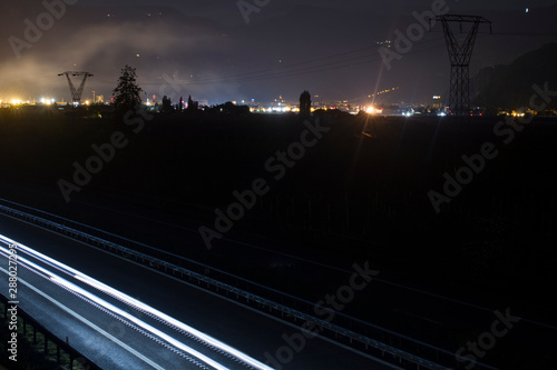 Two side Traffic on the A22 Autobahn in South Tirol, Bolzano in the Background. Long exposure of Light trails at night. photo