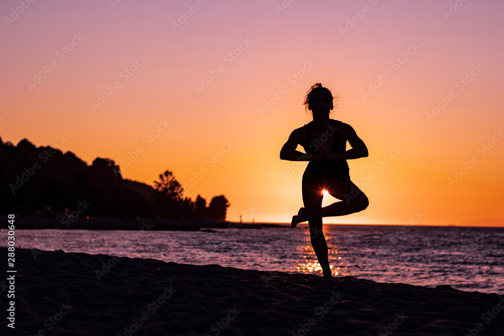 Woman in yoga position in tree pose at sunset on the beach, zen, relax, calm and serene Woman in yoga position in tree pose at sunset on the beach, zen, relax, calm and serene