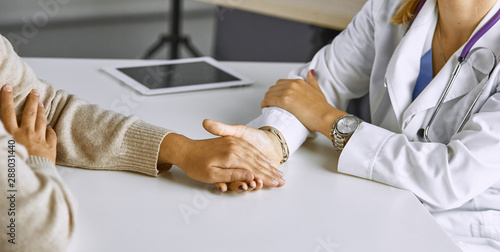 Woman doctor calms patient and holds hand