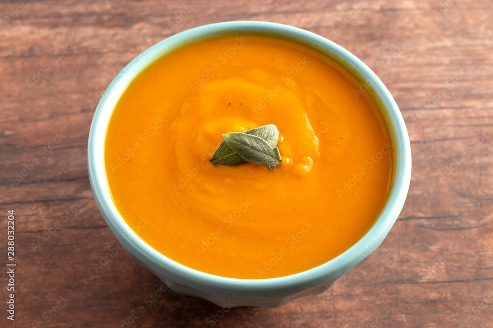 Bowl of Healthy Sweet Potato and Sage Soup on a Rustic Wooden Table Bowl of Healthy Sweet Potato and Sage Soup on a Rustic Wooden Table