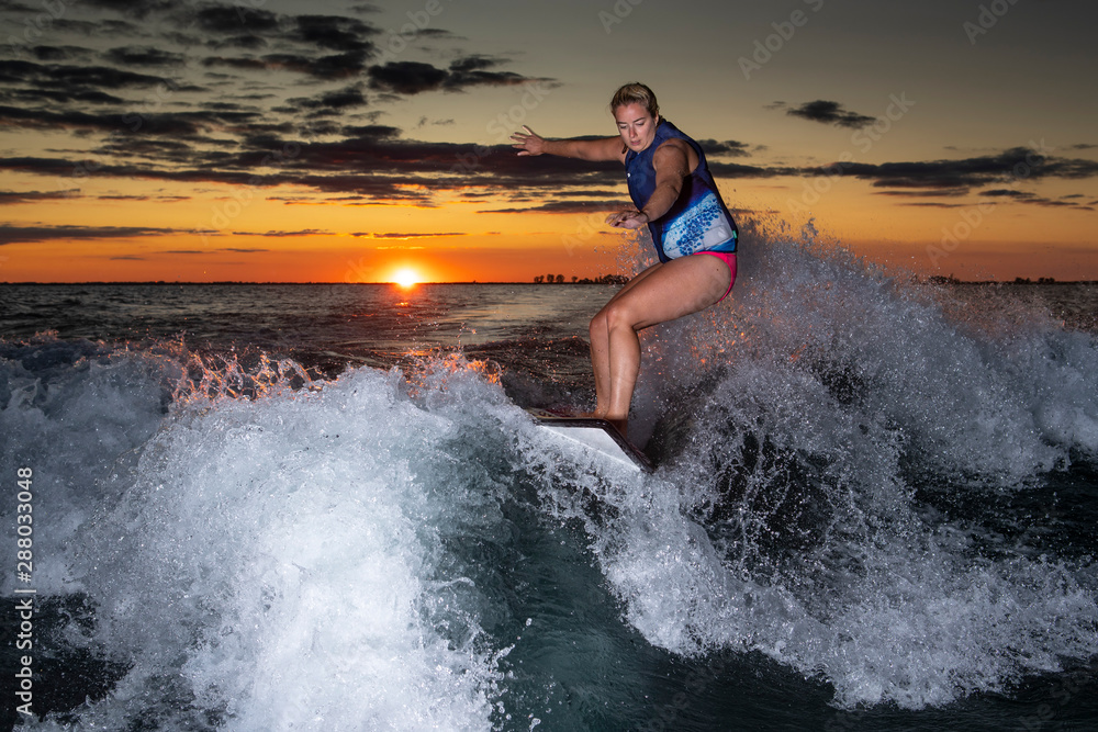 Woman wakesurfing at sunset.