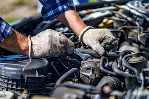 Auto mechanic repairing a car engine with a wrench. Repair service