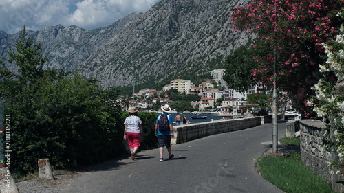 An elderly couple walks along a beautiful, small, street in the old town, among the sea, mountains, beautiful flowers