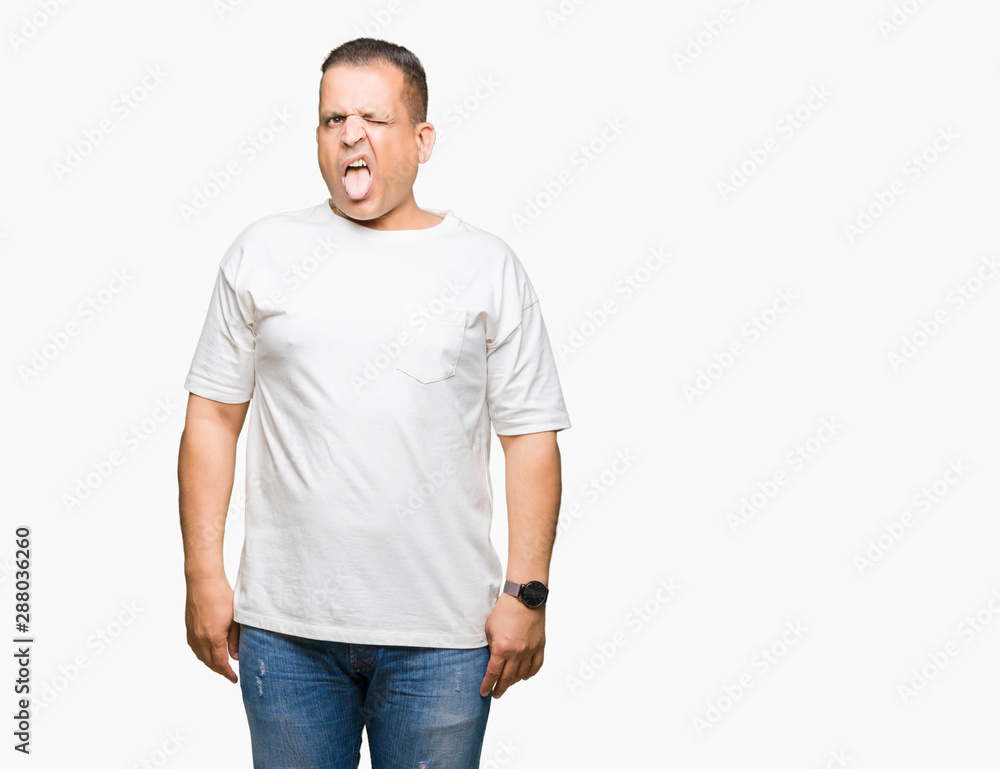 Middle age arab man wearig white t-shirt over isolated background sticking tongue out happy with funny expression. Emotion concept. Middle age arab man wearig white t-shirt over isolated background sticking tongue out happy with funny expression. Emotion concept.