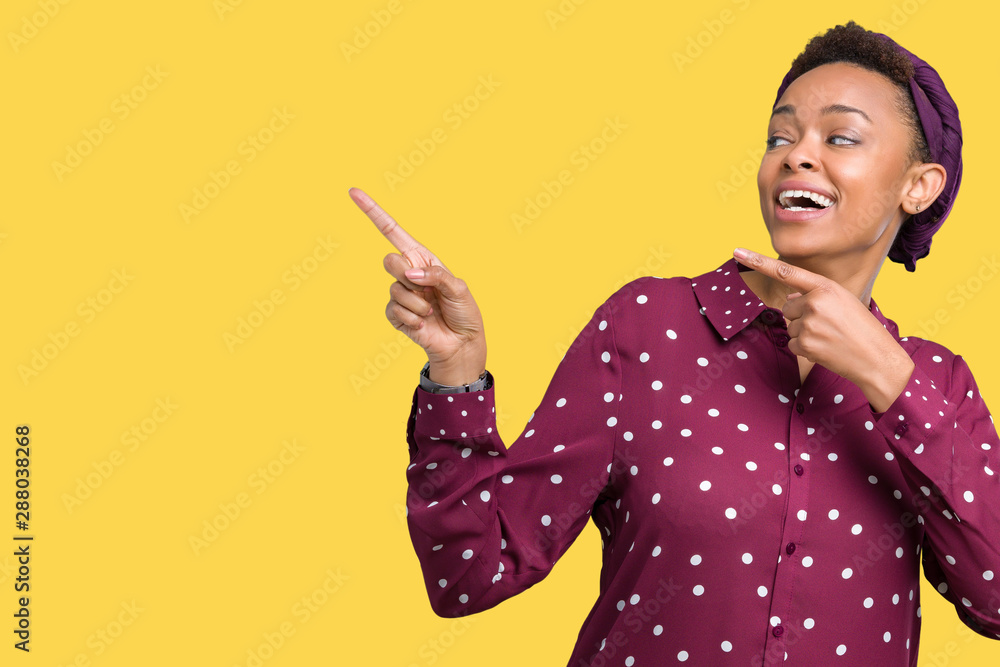 Beautiful young african american woman wearing head scarf over isolated background smiling and looking at the camera pointing with two hands and fingers to the side. Beautiful young african american woman wearing head scarf over isolated background smiling and looking at the camera pointing with two hands and fingers to the side.