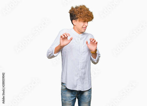 Young handsome business man with afro hair wearing elegant shirt disgusted expression, displeased and fearful doing disgust face because aversion reaction. With hands raised. Annoying concept.