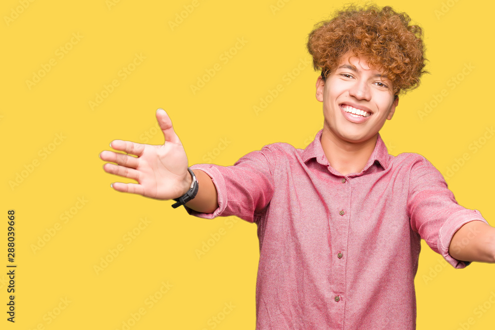 Young handsome business man with afro hair looking at the camera smiling with open arms for hug. Cheerful expression embracing happiness. Young handsome business man with afro hair looking at the camera smiling with open arms for hug. Cheerful expression embracing happiness.