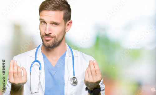 Фотография Handsome doctor man wearing medical uniform over isolated background Doing money