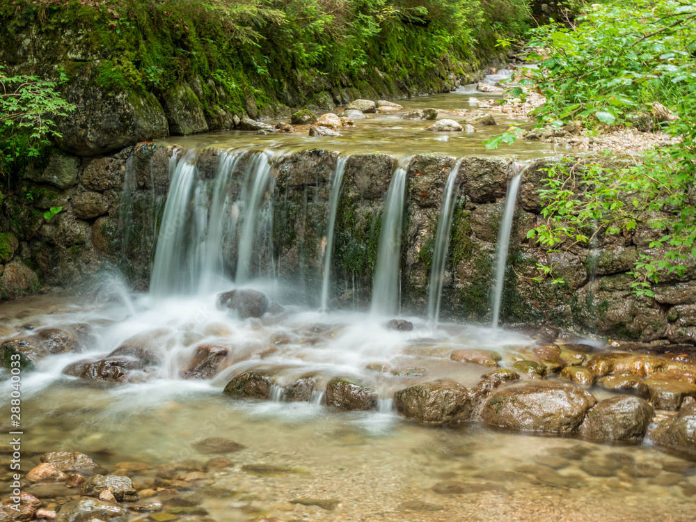Fototapeta premium Long exposure waterfall over rocks in forest landscape