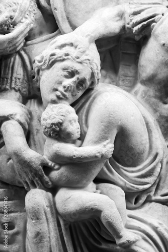 Detail of ancient engraved sculpture on marble showing woman protecting child - black and white photo