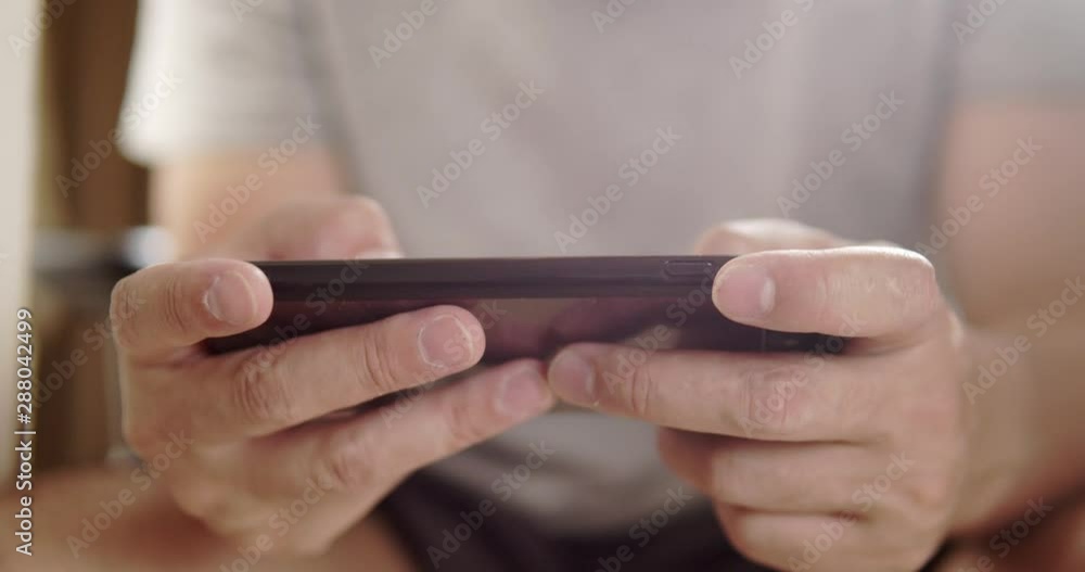 Asian man gamer close-up on his hand enjoy playing action online game on smart phone while sitting at his house.technology concept. Asian man gamer close-up on his hand enjoy playing action online game on smart phone while sitting at his house.technology concept.