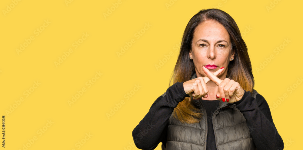 Beautiful middle age woman wearing winter vest Rejection expression crossing fingers doing negative sign Beautiful middle age woman wearing winter vest Rejection expression crossing fingers doing negative sign