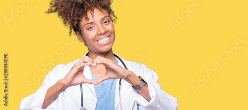 Young african american doctor woman over isolated background smiling in love showing heart symbol and shape with hands. Romantic concept. photo