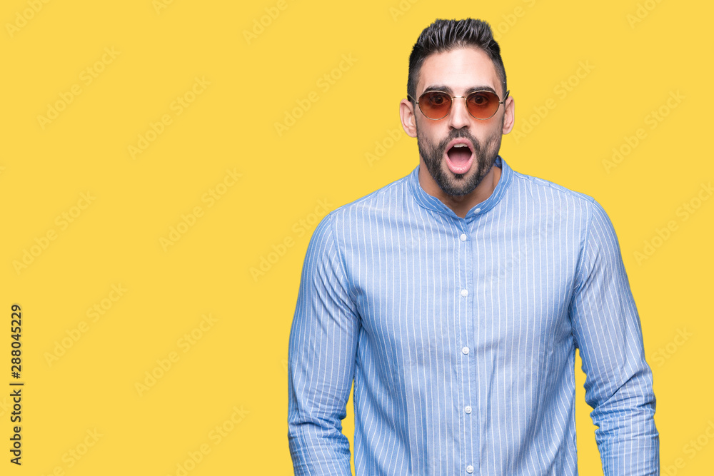 Young handsome man wearing sunglasses over isolated background afraid and shocked with surprise expression, fear and excited face. Young handsome man wearing sunglasses over isolated background afraid and shocked with surprise expression, fear and excited face.