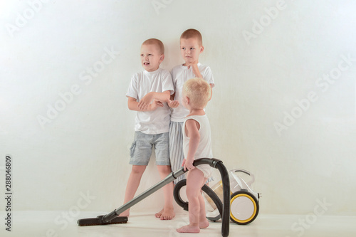 Caucasian blond brothers do the cleaning in their room. White isolated background, interior. photo