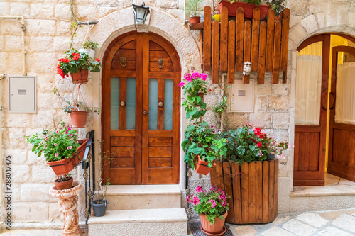 Italy, Apulia, Metropolitan City of Bari, Bari. Wooden doors and potted flowers on a stone building.