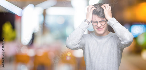 Young handsome man wearing glasses over isolated background suffering from headache desperate and stressed because pain and migraine. Hands on head.