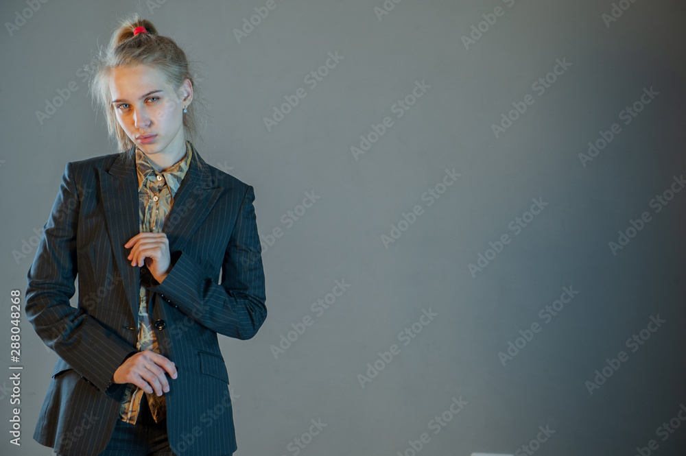 Fototapeta premium beautiful blonde with blue eyes in business trouser suit posing in front of camera. Young woman actress actively expresses her emotions and touches her hair