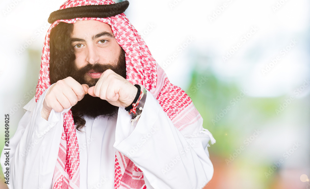 Arabian business man with long hair wearing traditional keffiyeh scarf Ready to fight with fist defense gesture, angry and upset face, afraid of problem