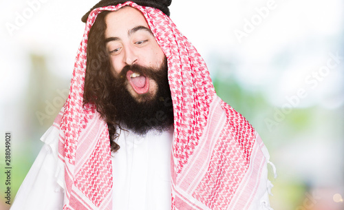 Quadro su tela Arabian business man with long hair wearing traditional keffiyeh scarf making fish face with lips, crazy and comical gesture
