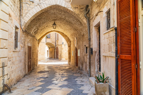 Fototapeta Naklejka Na Ścianę i Meble -  Italy, Apulia, Metropolitan City of Bari, Giovinazzo. Narrow street with stone arches.
