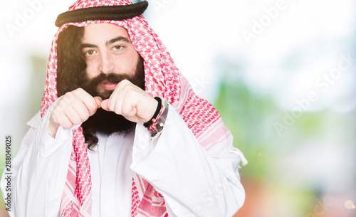 Arabian business man with long hair wearing traditional keffiyeh scarf Ready to fight with fist defense gesture, angry and upset face, afraid of problem