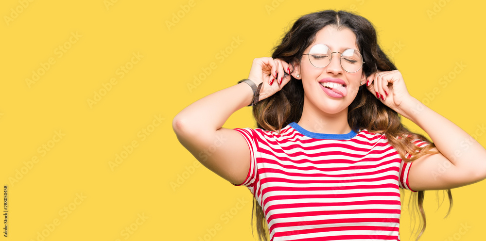 Young beautiful woman wearing glasses Smiling pulling ears with fingers, funny gesture. Audition problem Young beautiful woman wearing glasses Smiling pulling ears with fingers, funny gesture. Audition problem
