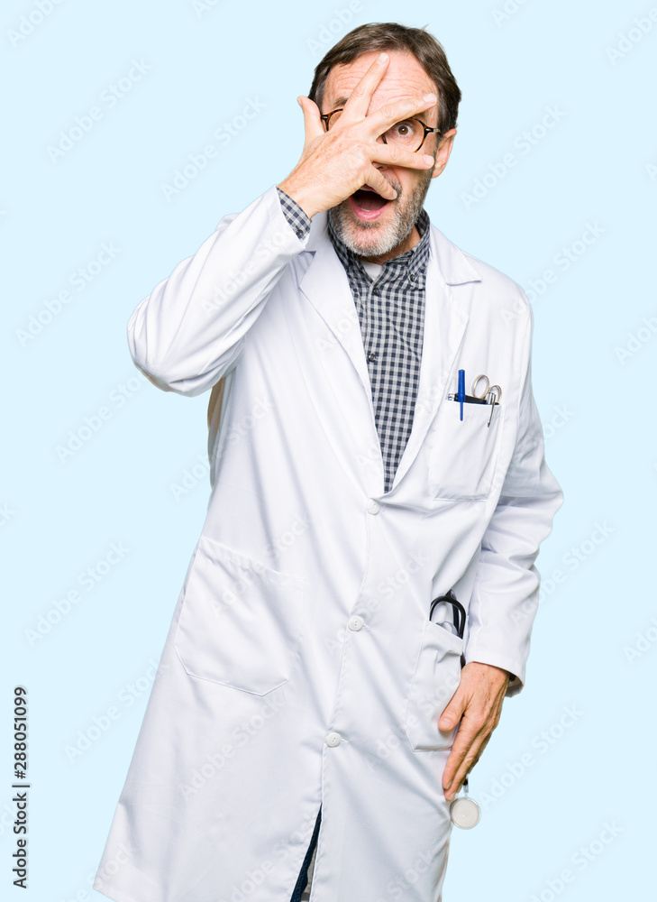 Middle age doctor men wearing medical coat peeking in shock covering face and eyes with hand, looking through fingers with embarrassed expression. Middle age doctor men wearing medical coat peeking in shock covering face and eyes with hand, looking through fingers with embarrassed expression.