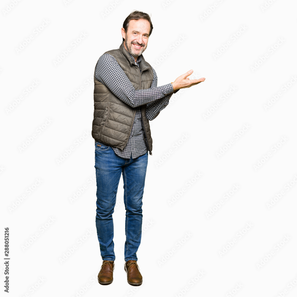 Middle age handsome man wearing winter vest Pointing to the side with hand and open palm, presenting ad smiling happy and confident Middle age handsome man wearing winter vest Pointing to the side with hand and open palm, presenting ad smiling happy and confident