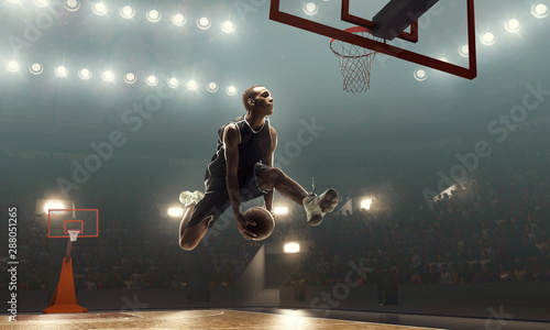 African american basketball player in action on a floodlit court. Slam dunk  © TandemBranding