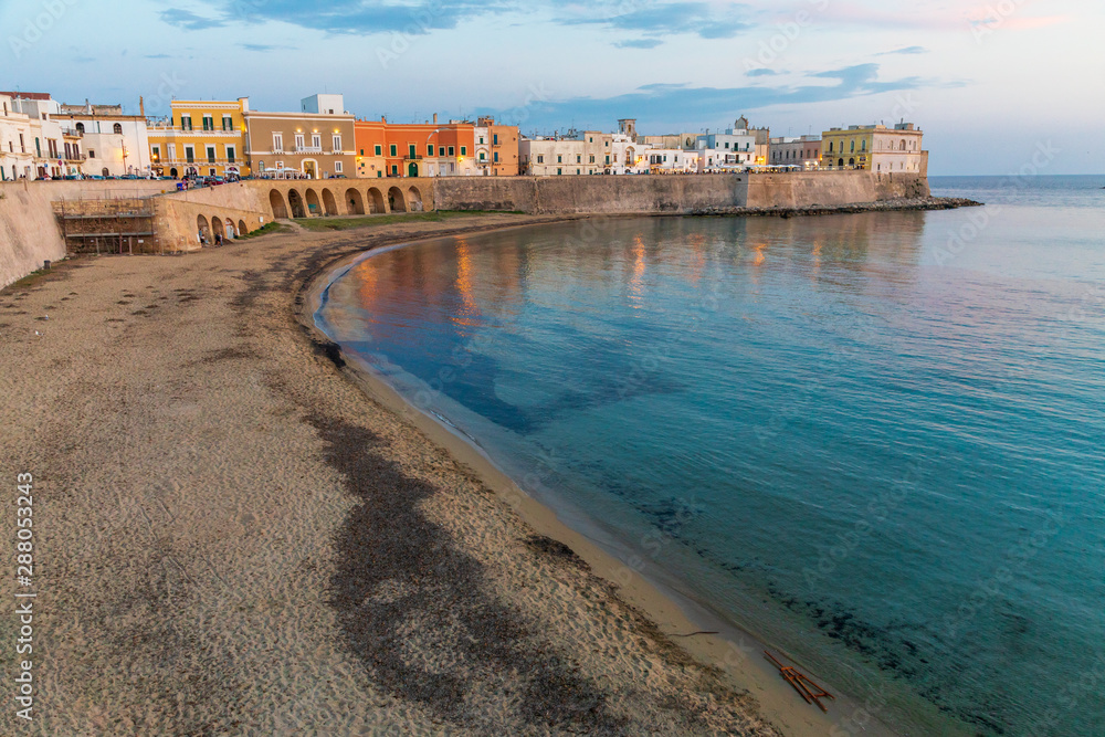 Italy, Apulia, Province of Lecce, Gallipoli. Beach and old town section over the Ionian Sea at sunset.