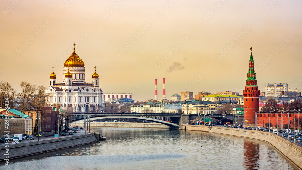 Panoramic cityscape with beautiful Cathedral of Christ the Saviour and Kremlin Vodovzvodnaya Tower view from Moskva River golden sunrise Moscow Russia