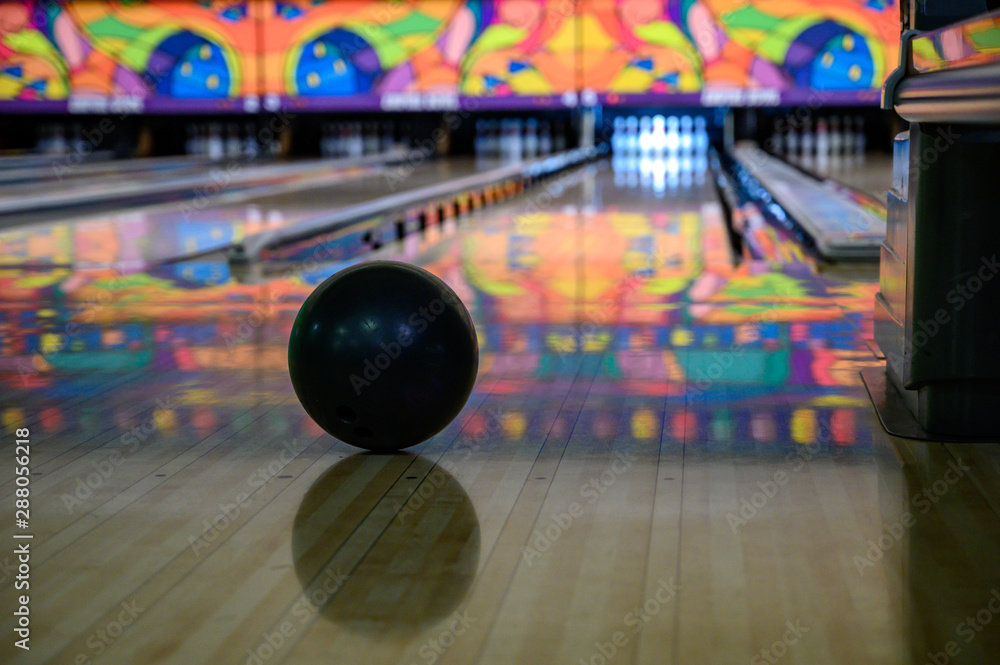 Bowling ball in focus with blurred view down bowling alley with gutter