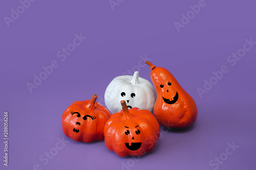 Pumpkins with funny faces on violet background, creative concept. Festive advertising flat lay banner, front view. Decor for celebration. Modern trendy halloween composition with copy space