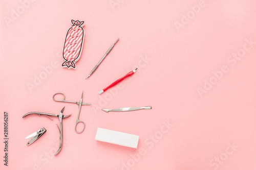 Manicure concept set on pink background. Tools for perfect nails, polishing nail buff, cuticle pusher, cuticle trimmer, nail file, nail scissors, toes separator, nail clippers, toenail clippers.