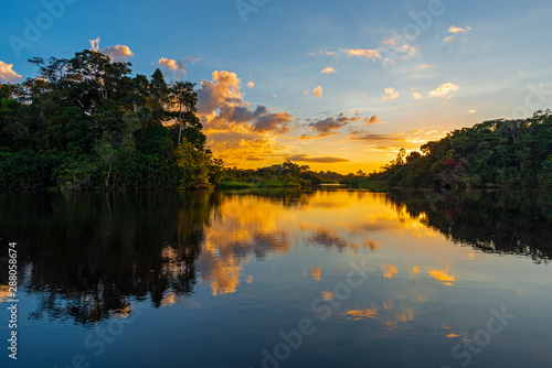 Reflection of a sunset by a lagoon inside the Amazon Rainforest Basin. The Amazon river basin comprises the countries of Brazil, Bolivia, Colombia, Ecuador, Guyana, Suriname, Peru and Venezuela. photo