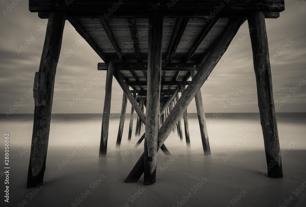 Under old wooden fishing pier with calm ocean