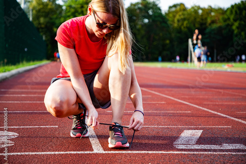 young woman on running track lacing her shoes