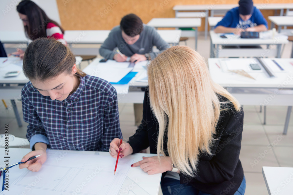 Fototapeta premium Female Architecture teacher at work. Female professor explain architectural projects to students. Beautiful female university architecture professor explain lessons to multiethnic students.