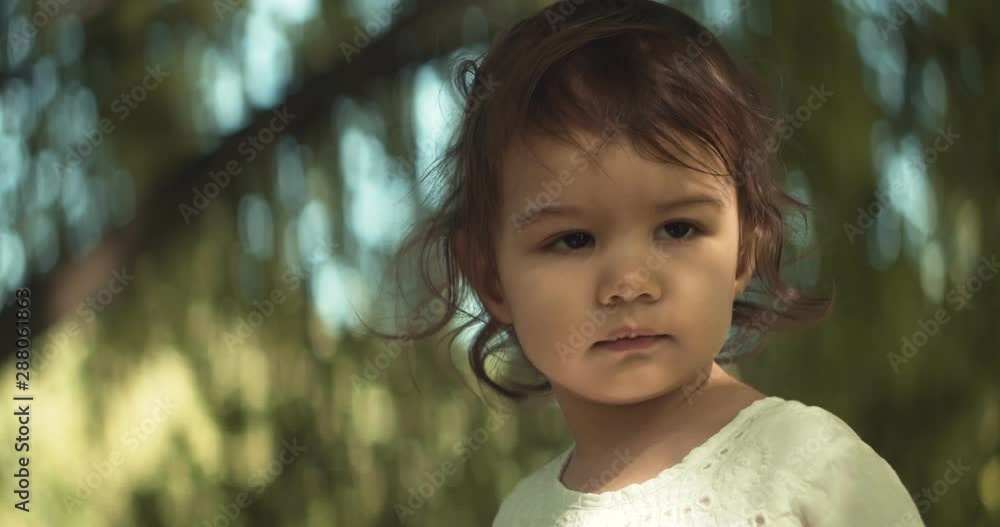 Cute baby girl exploring a park in summer. Real life, candid 4K footage. Anamorphic bokeh.