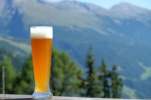 Weissbier or white beer in  German Hefeweizen glass on wooden table.  photo