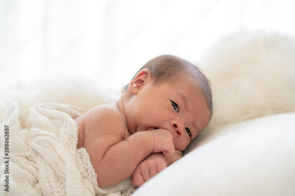 Selective focus medium shot of 0-1 months beautiful relax asian newborn baby girl infant lying down on the soft white blanket baby sleeper. Mother and young baby health care concept.