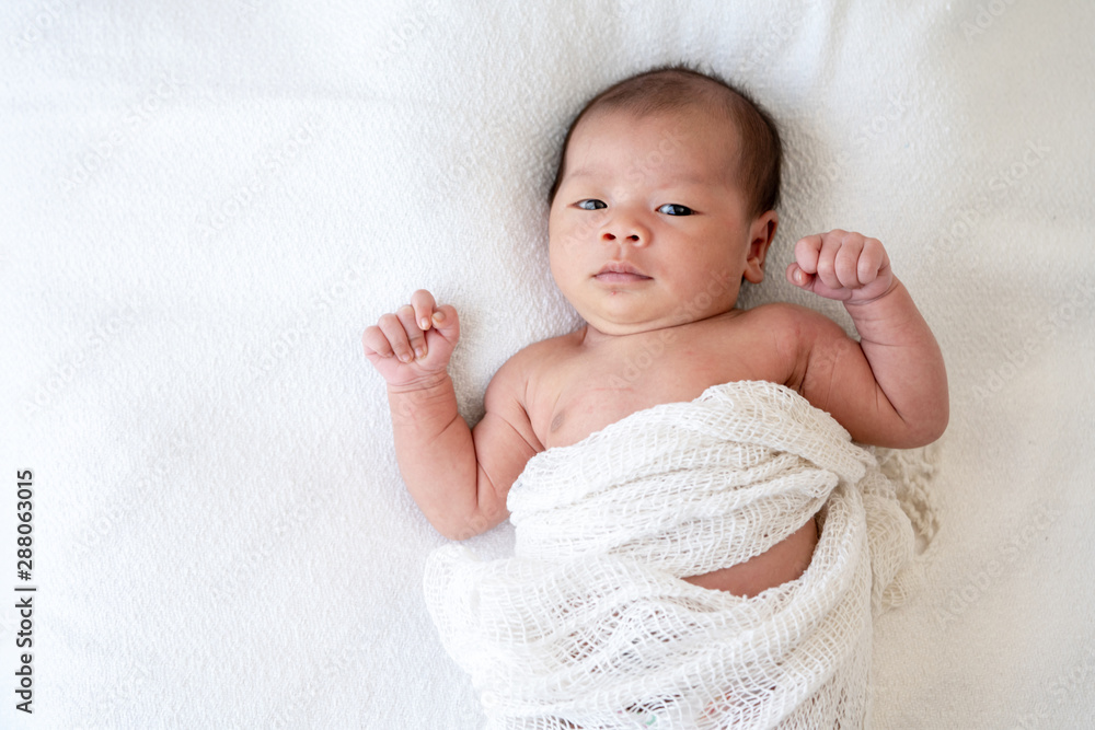 Selective focus medium shot of 0-1 months beautiful relax asian newborn baby girl infant lying down on the soft white blanket baby sleeper. Mother and young baby health care concept. Selective focus medium shot of 0-1 months beautiful relax asian newborn baby girl infant lying down on the soft white blanket baby sleeper. Mother and young baby health care concept.