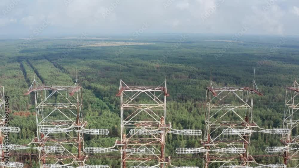 Aerial view of Soviet over-the-horizon radar system, abandoned due to accident at Chernobyl nuclear plant. Tops of giant steel construction Duga on background of green forest in exclusion zone Aerial view of Soviet over-the-horizon radar system, abandoned due to accident at Chernobyl nuclear plant. Tops of giant steel construction Duga on background of green forest in exclusion zone