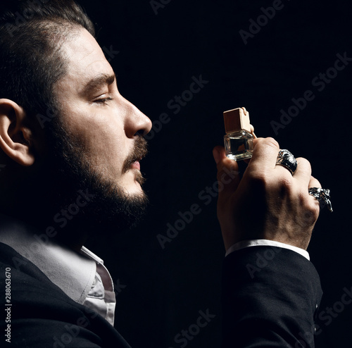 Brutal man with beard and modern hairstyle smell auto perfume wear business classic suit photo