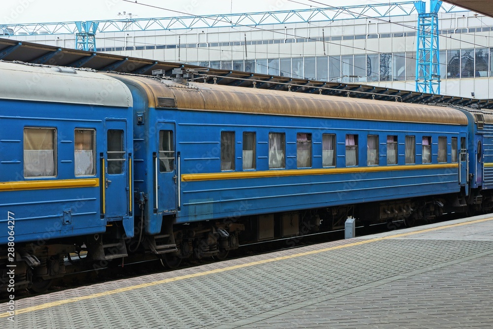 blue passenger car with windows stands at the railway station