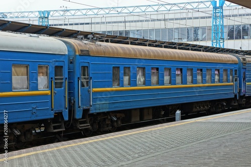 blue passenger car with windows stands at the railway station