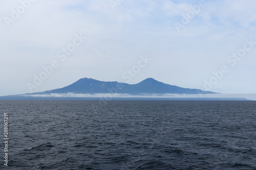 Iturup Island volcanoes on foggy horizon. The Sea of Okhotsk, Kuril Islands, Russia, claimed by Japan.