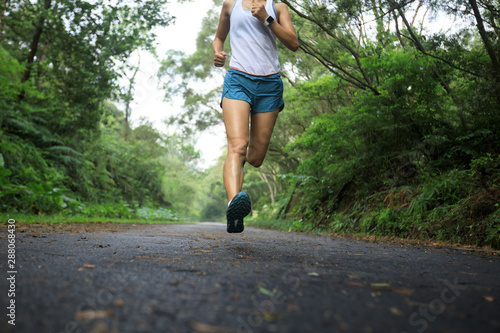 Female runner running at summer park trail . Healthy fitness woman jogging outdoors. © lzf